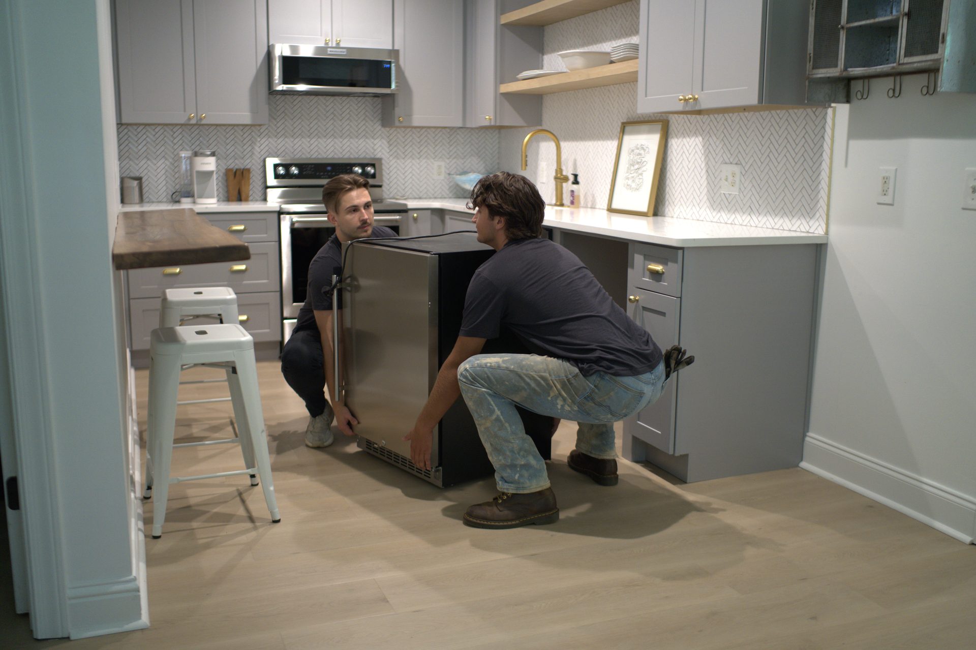 Two service professionals installing an appliance in a homeowner's kitchen